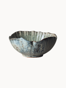 Rustykalna ceramiczna miska pokryta melanżowym jasnoniebieskim i beżowym szkliwem z brązowymi, nakrapianymi detalami na jednolitym białym tle.